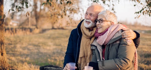 Portrait of a senior couple enjoying coffee in the nature after hiking.