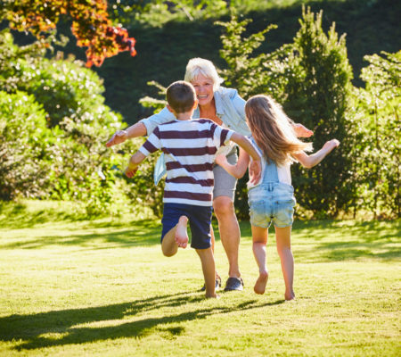 Grandchildren running to grandmother in sunny garden