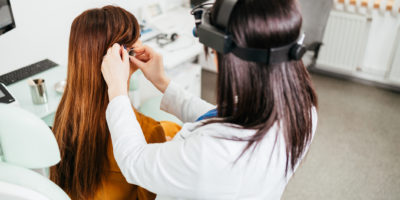 Beautiful middle age brunette woman receiving medical treatment. Hearing aid checkup. Otolaryngology.