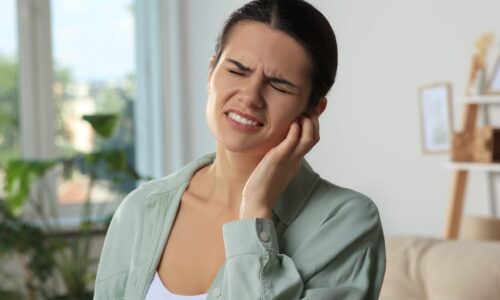 Young woman suffering from ear pain at home Young woman suffering from ear pain at home